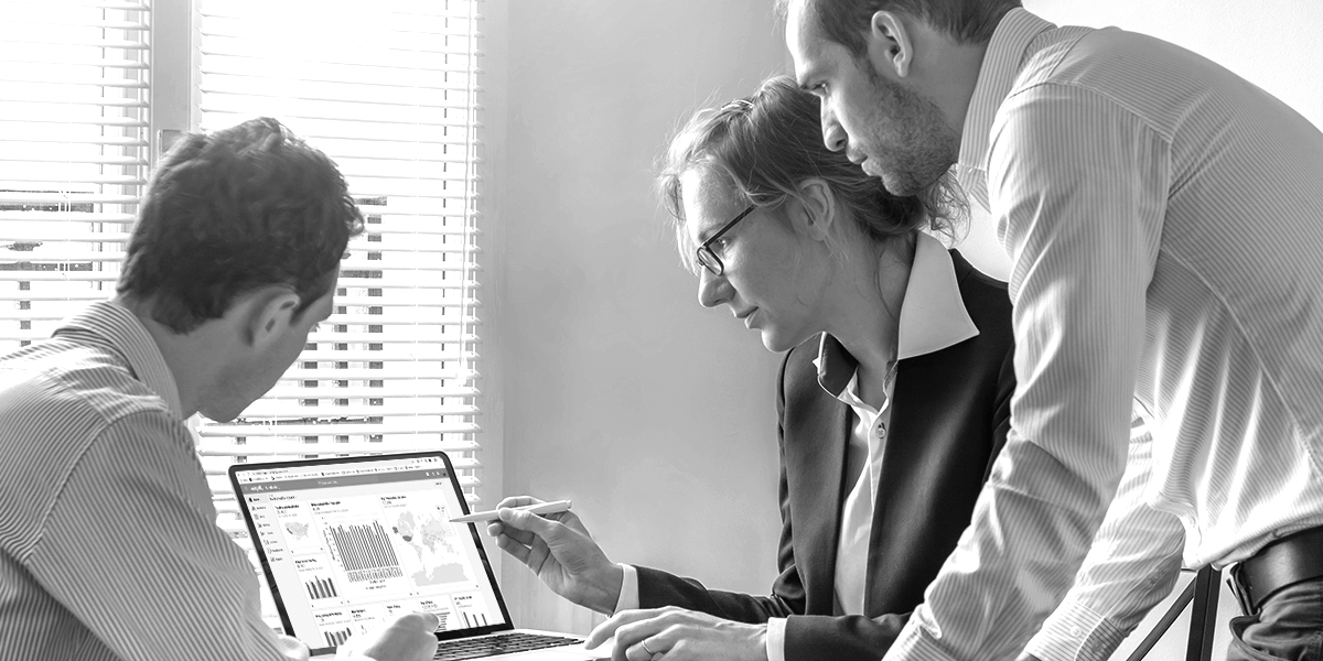Three people in an office, looking at data on a computer screen.