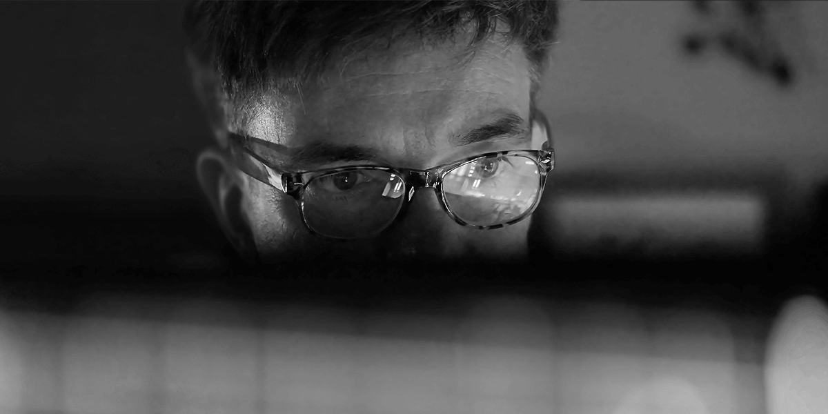 Person in glasses closely examining a computer screen.