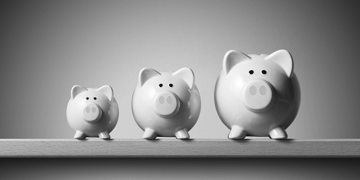 Three piggy banks sized small, medium, and large on a surface beside each other
